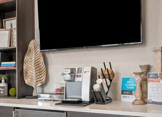 A kitchen counter with a TV above it and a refrigerator below.