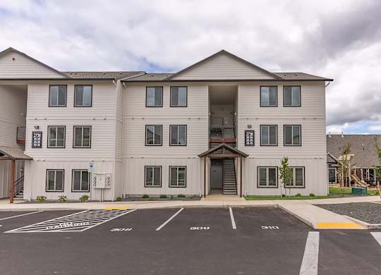 A large apartment building with a parking lot in front at Marcola Apartment Homes, Forest Grove, 97477
