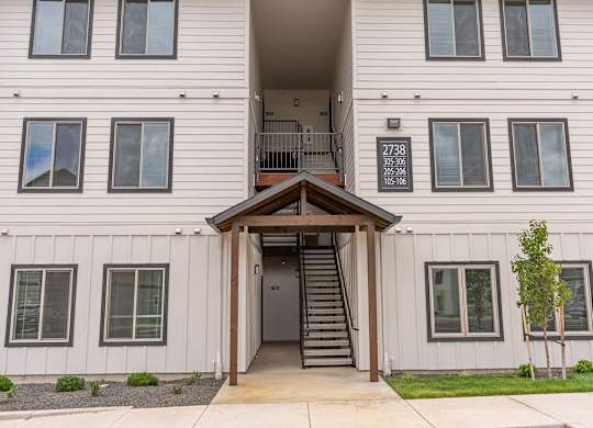 A white building with a brown roof and a staircase leading to the entrance at Marcola Apartment Homes, Forest Grove, Oregon
