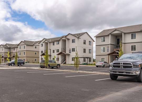 A parking lot with cars and apartment buildings in the background at Marcola Apartment Homes, Forest Grove, 97477