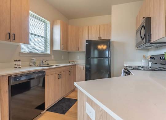 A kitchen with a black fridge and wooden cabinets at Marcola Apartment Homes, Forest Grove, OR, 97477