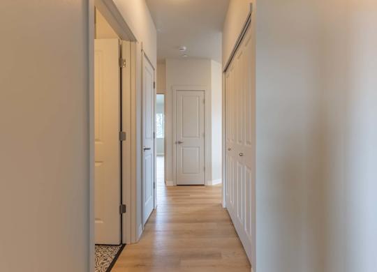 A long hallway with white doors and a wooden floor at Marcola Apartment Homes, Forest Grove, Oregon