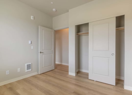 A room with white walls and wooden floors, featuring a white door and a white cabinet at Marcola Apartment Homes, Forest Grove, 97477