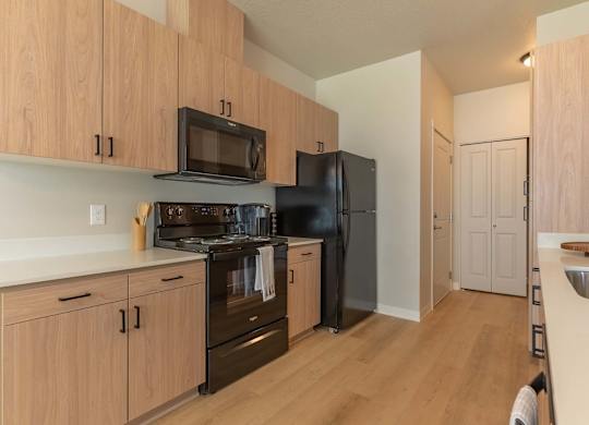 A kitchen with wooden cabinets and black appliances at Marcola Apartment Homes, Forest Grove, Oregon
