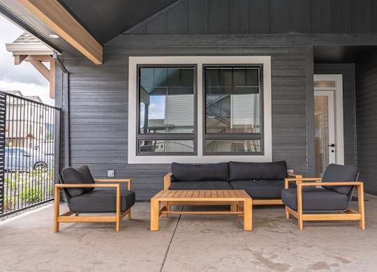 A grey house with a black sofa and two chairs on the porch at Marcola Apartment Homes, Oregon, 97477