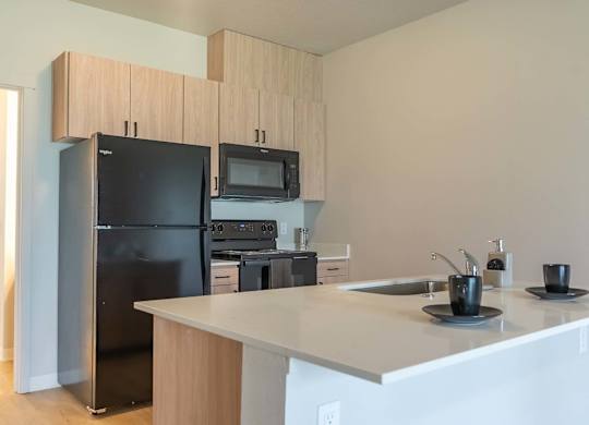 A kitchen with black appliances and white countertops at Marcola Apartment Homes, Forest Grove, OR