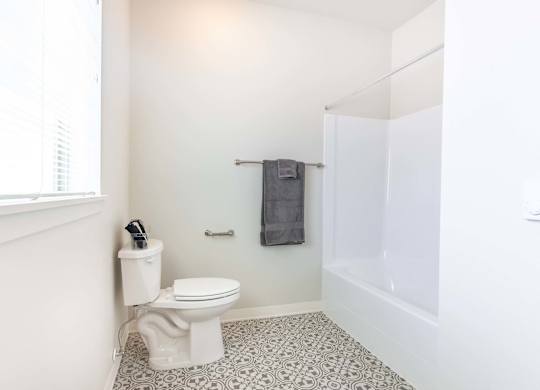 A white toilet sits in a bathroom with a white wall and a white floor at Marcola Apartment Homes, Oregon, 97477