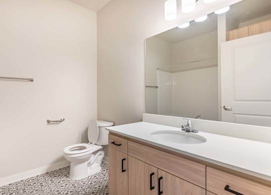 A bathroom with a toilet, sink, and mirror at Marcola Apartment Homes, Forest Grove, OR