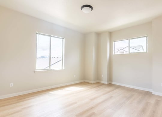 A room with wooden floors and two windows at Marcola Apartment Homes, Forest Grove, OR