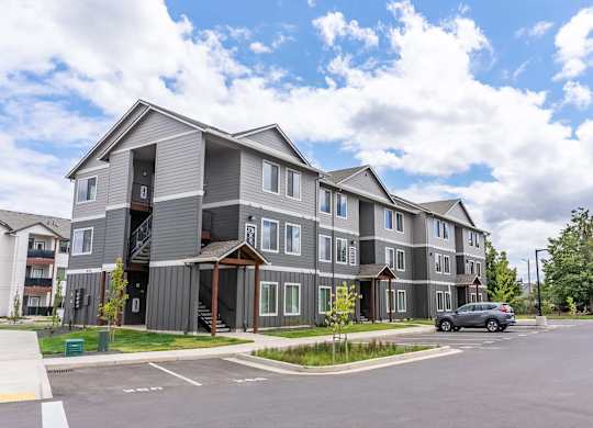 A grey apartment building with a car parked in front at Marcola Apartment Homes, Forest Grove, OR, 97477