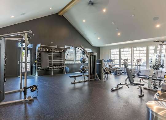A spacious gym with a variety of equipment including a squat rack, bench, and weights at Westgate Apartment Homes, Pendleton, OR, 97801