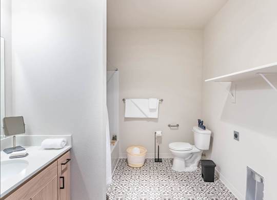 A bathroom with a toilet, sink, and a trash can at Westgate Apartment Homes, Pendleton, 97801