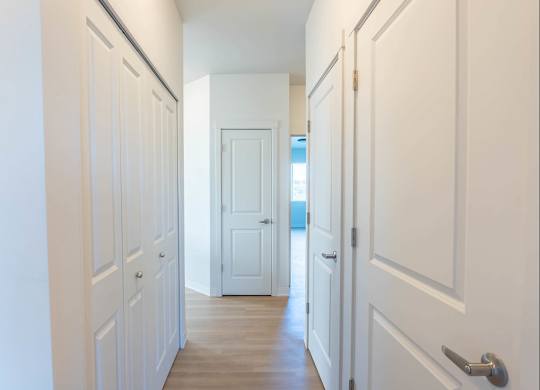 A long hallway with white doors and a wooden floor at Westgate Apartment Homes, Oregon, 97801