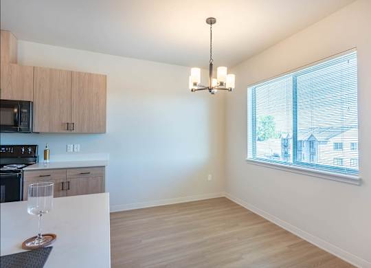 A kitchen with a microwave, oven, and a dining table with a wine glass on it at Westgate Apartment Homes, Pendleton, OR, 97801