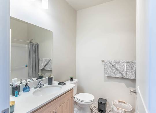 A bathroom with a white sink, toilet, and a mirror at Westgate Apartment Homes, Pendleton, OR