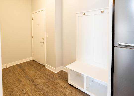 A kitchen with a refrigerator, a door, and a shelf.