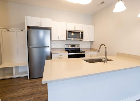 A kitchen with a white counter top and a black refrigerator.
