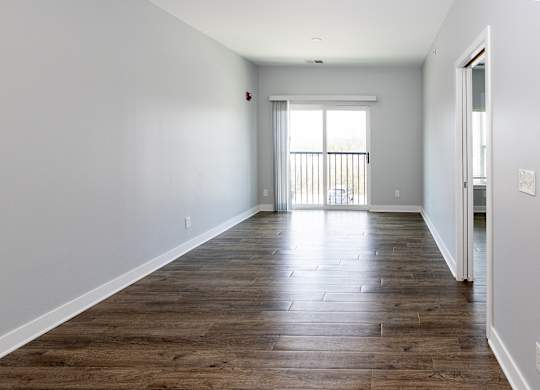A long, empty room with wooden floors and white walls.