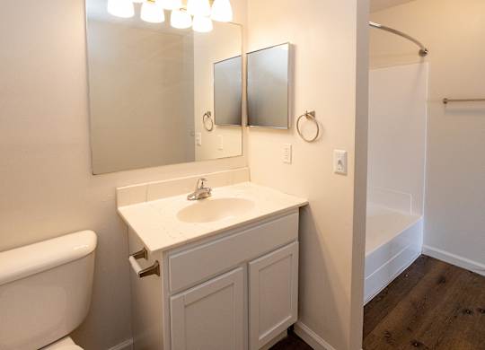 A white bathroom with a sink, mirror, and toilet.