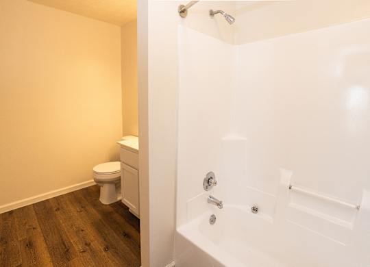 A white bathtub with a shower head and a toilet in a bathroom.