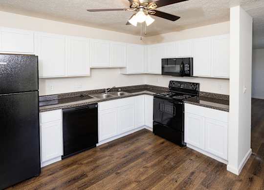 A kitchen with black appliances and white cabinets.