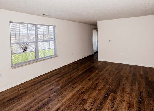 Empty room with wooden flooring and a window.