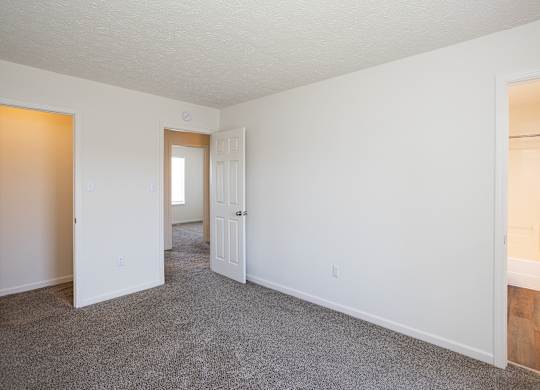 A room with white walls and a grey carpet.