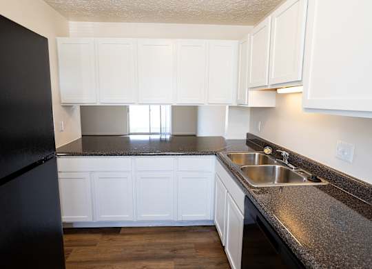 A kitchen with black fridge and white cabinets.