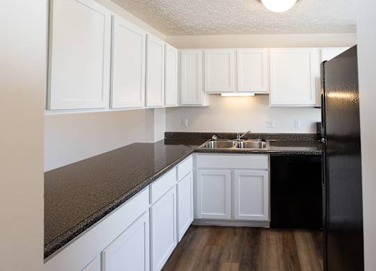 A kitchen with white cabinets and a black refrigerator.