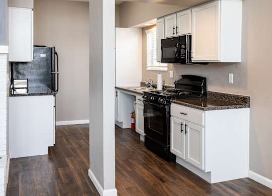 A kitchen with black appliances and white cabinets.