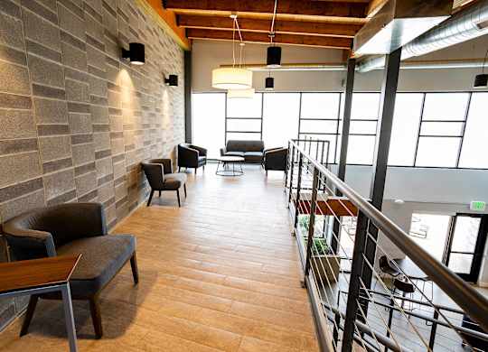 A long hallway with a couch and chairs on the left and a railing on the right.