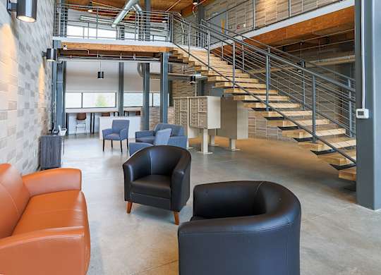 A modern interior with a staircase and leather chairs.