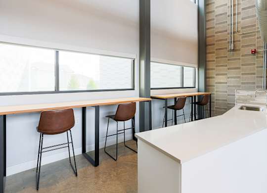 A white kitchen with a bar area and brown chairs.