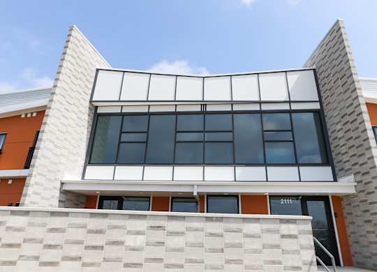 A modern building with a white and orange facade and a large glass window.