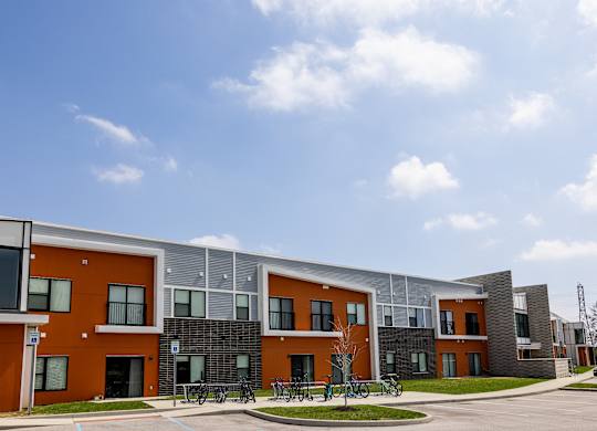 A modern building with orange and grey exterior and a clear blue sky above.