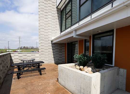A patio with a table and a bench outside a house.