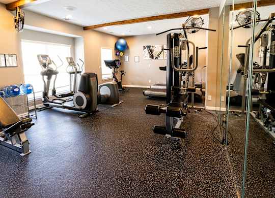 A spacious gym with a variety of equipment including a treadmill, weights, and a bench press.