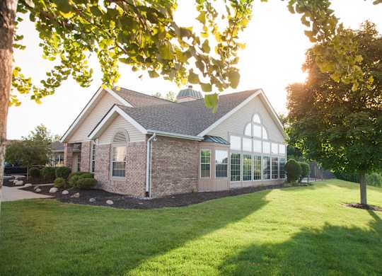 A house with a green lawn and trees in the background.