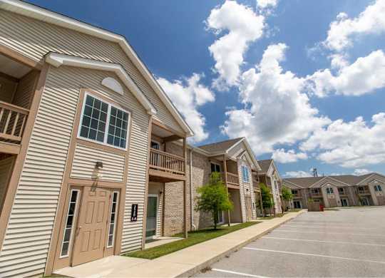 A row of apartment buildings with a parking lot in front.