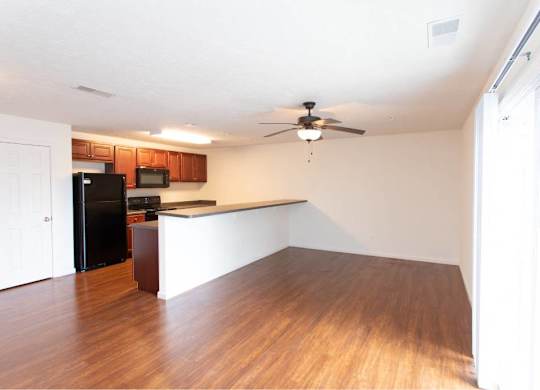 A room with a ceiling fan and wooden flooring.