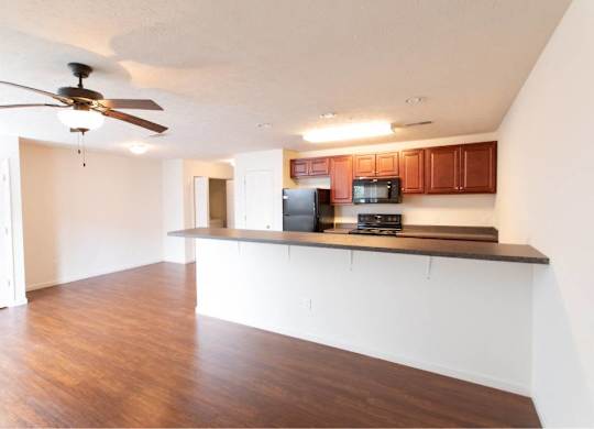 A kitchen with brown cabinets and a black refrigerator.