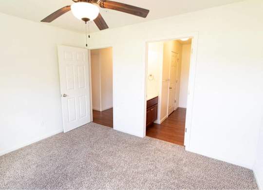 A room with a ceiling fan and carpeted floor.