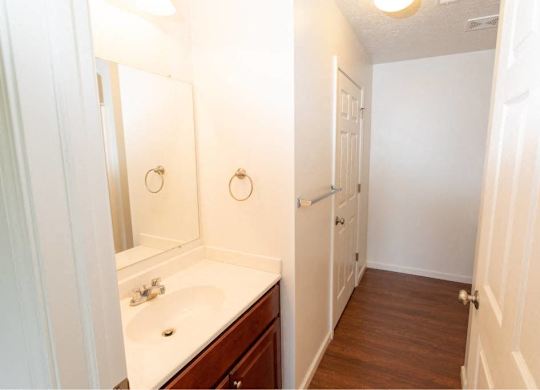 A white bathroom with a wooden floor and a white sink.