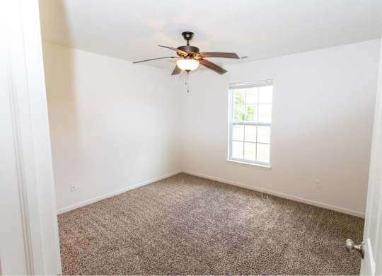 A room with a ceiling fan and a window.