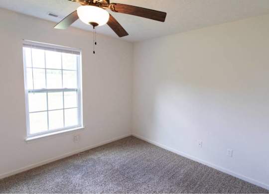 A room with a ceiling fan and a window.