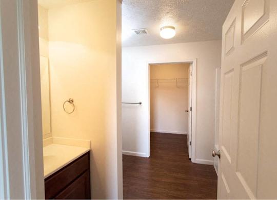 A white bathroom with a wooden vanity and a white door.