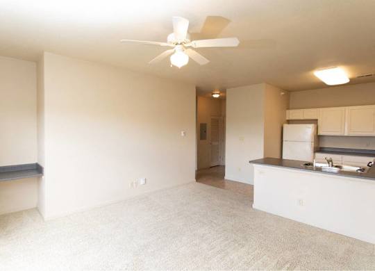 A room with a ceiling fan and a kitchenette.