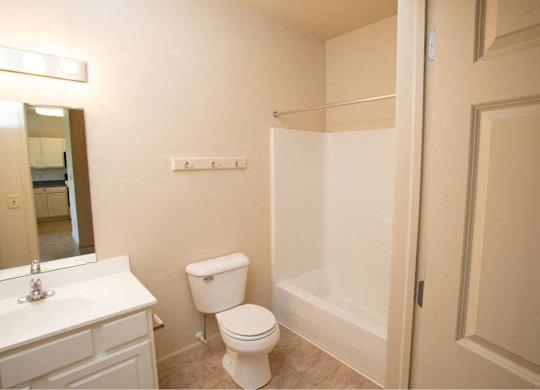 A white toilet sits in a bathroom next to a sink and a shower.