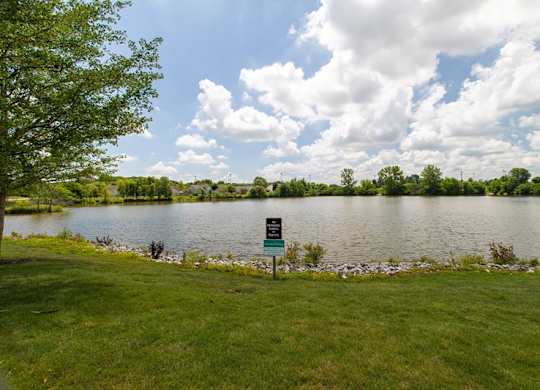 A sign is in the grass by a lake.