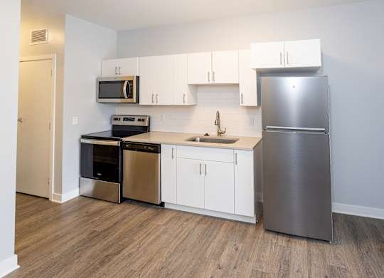A kitchen with a stainless steel refrigerator, microwave, oven, and sink.
